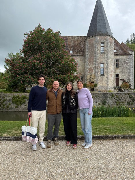 Four people standing in front of a historic building with a clock tower.