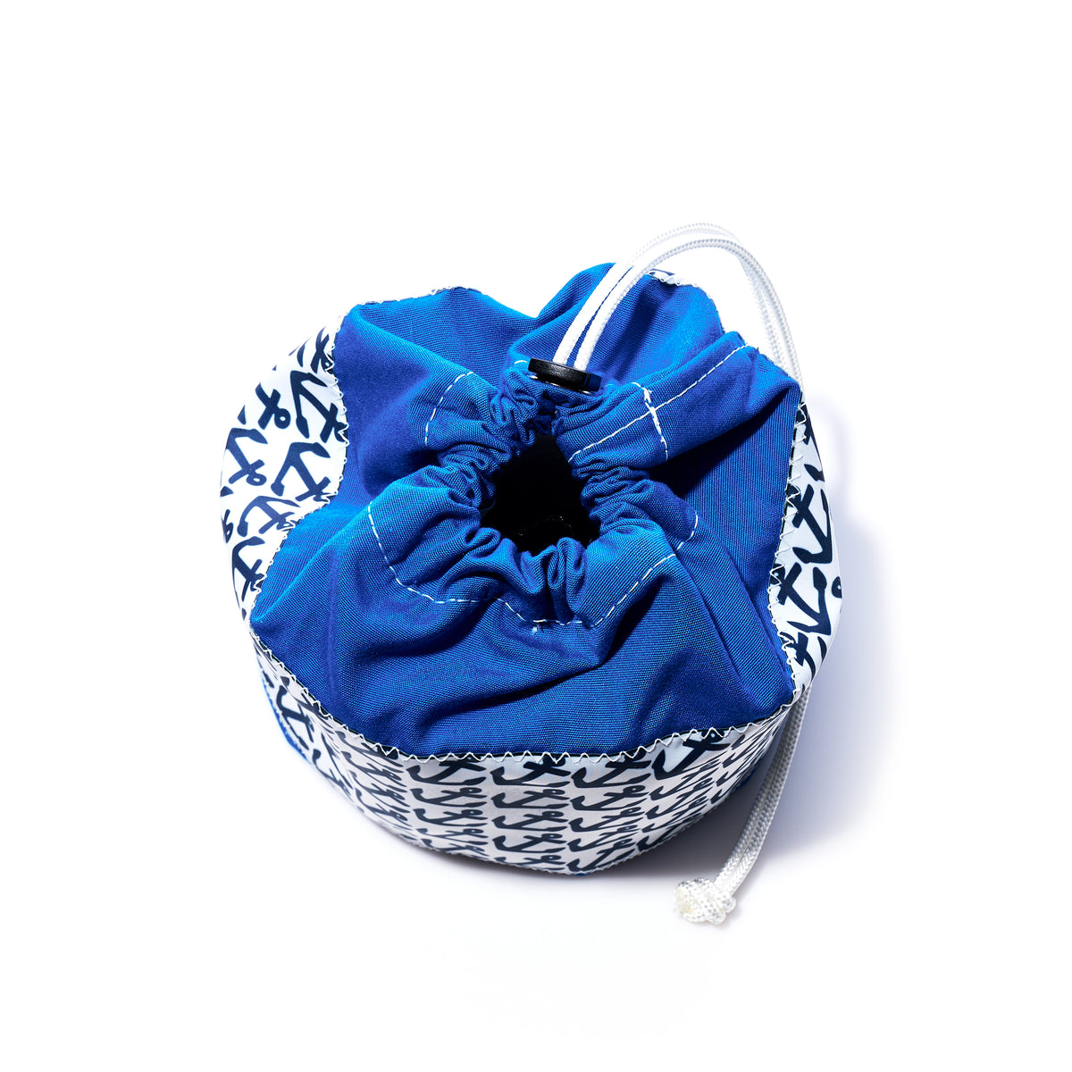 The Anchor Pop Ditty Bag by Sea Bags is a small, round sail cloth bag with a blue drawstring top and white sides accented by a navy blue abstract pattern, shown against a white background.