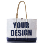 The Sea Bags Custom Design Ogunquit Beach Tote is a white and navy beach bag with rope handles, featuring YOUR DESIGN printed in large, bold blue letters on the front—an ideal personalized accessory crafted for both style and convenience. by Sea Bags
