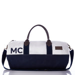 Introducing the Custom Chebeague Duffel by Sea Bags—a chic two-tone carryall designed with a crisp white top, deep navy bottom, and sturdy dark handles. Personalized with MC initials on the side, this duffel is the ideal companion for your next getaway. by Sea Bags