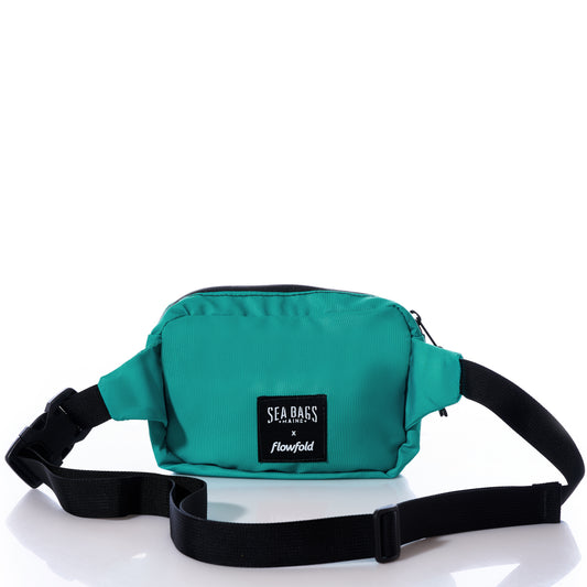 The Multicolor Nautilus Belt Bag by Sea Bags is crafted from recycled sail cloth in teal, featuring a black adjustable waistband and a front label that reads Sea Bags x Flowfold on a white background. by Sea Bags