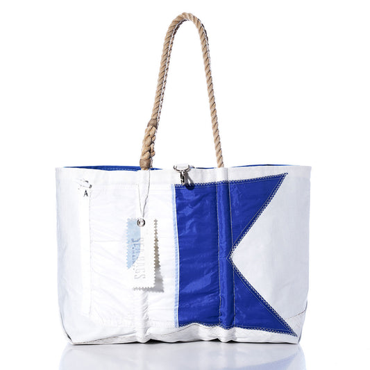 Sea Bags Alpha Signal Flag Large Tote, crafted from recycled sail cloth in white and blue with a rope handle and a tag attached, displayed against a white background. by Sea Bags