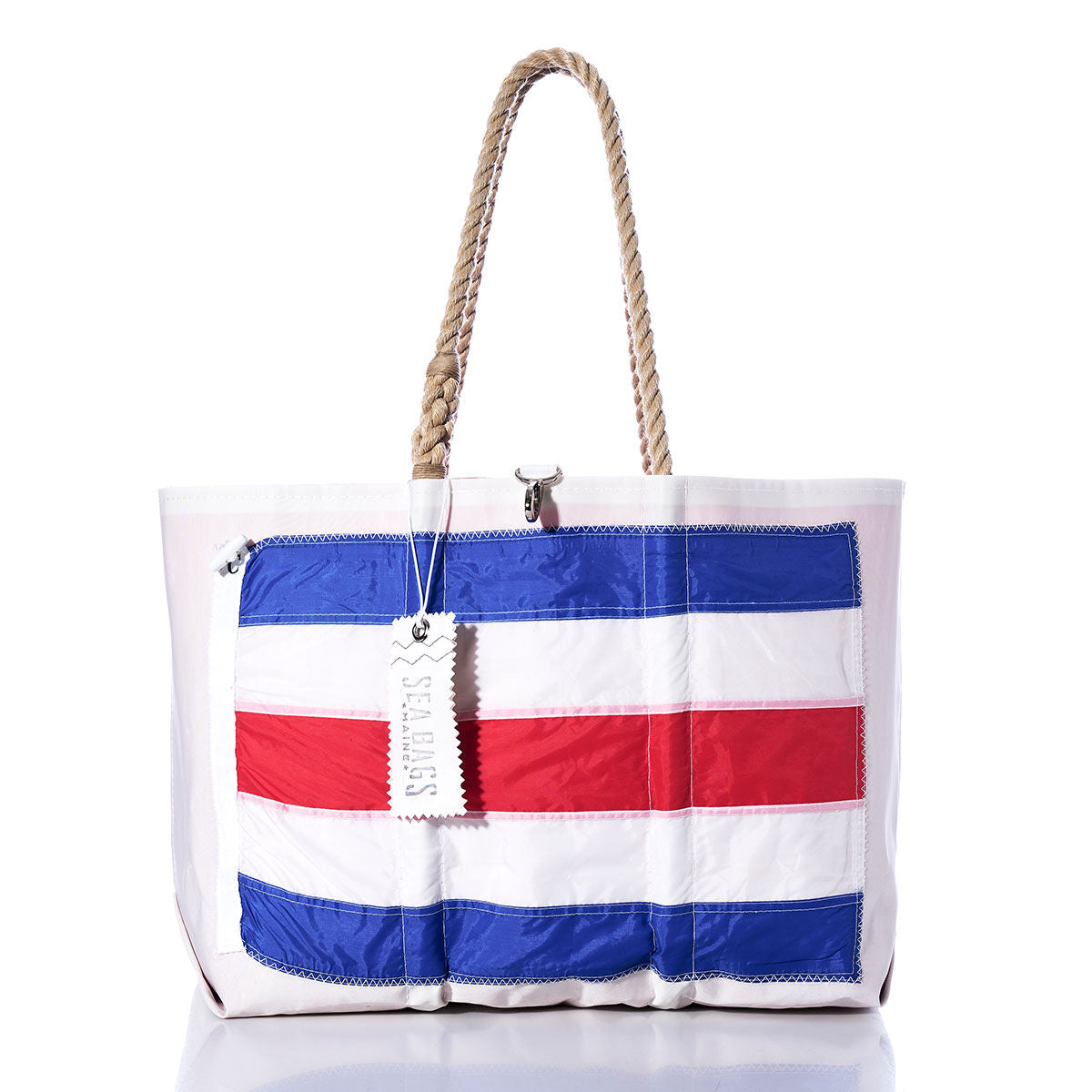 Introducing the Charlie Signal Flag Large Tote by Sea Bags—a limited-edition white tote crafted from vintage sail cloth. This striking bag features rope handles and a bold blue and red striped panel on the front, inspired by maritime signal flags. Finished with a signature Sea Bags silver tag, it’s both unique and stylish. by Sea Bags