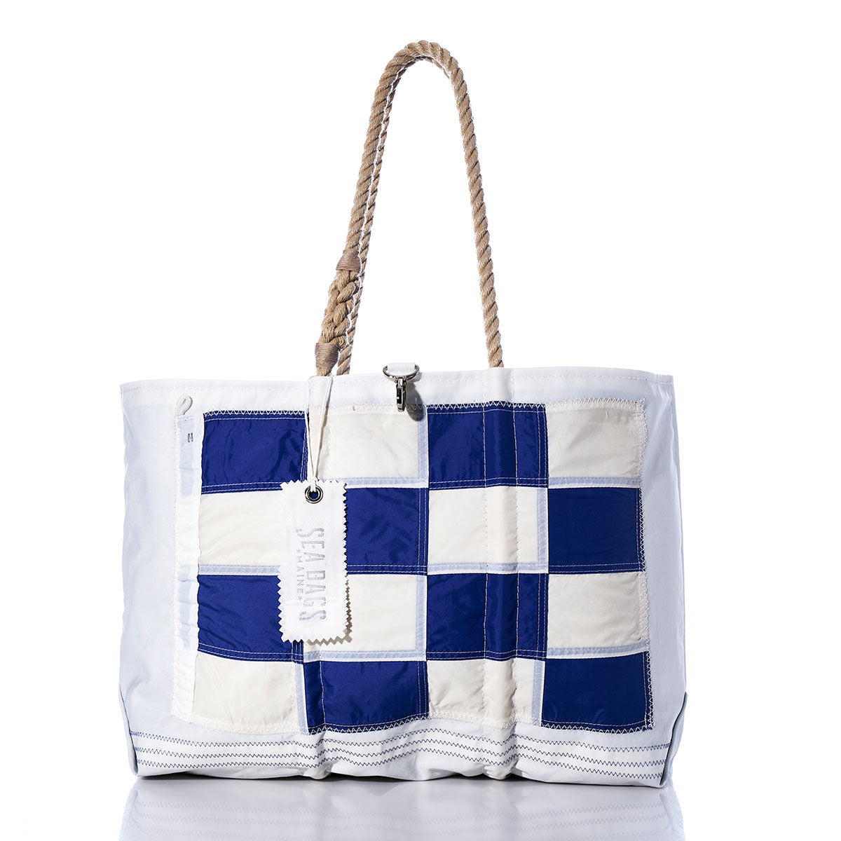 November Signal Flag Large Tote by Sea Bags, featuring navy blue and white checkered panels inspired by vintage signal flags, rope handles, a white Sea Bags tag, and crafted from recycled sail cloth—shown on a white background. by Sea Bags