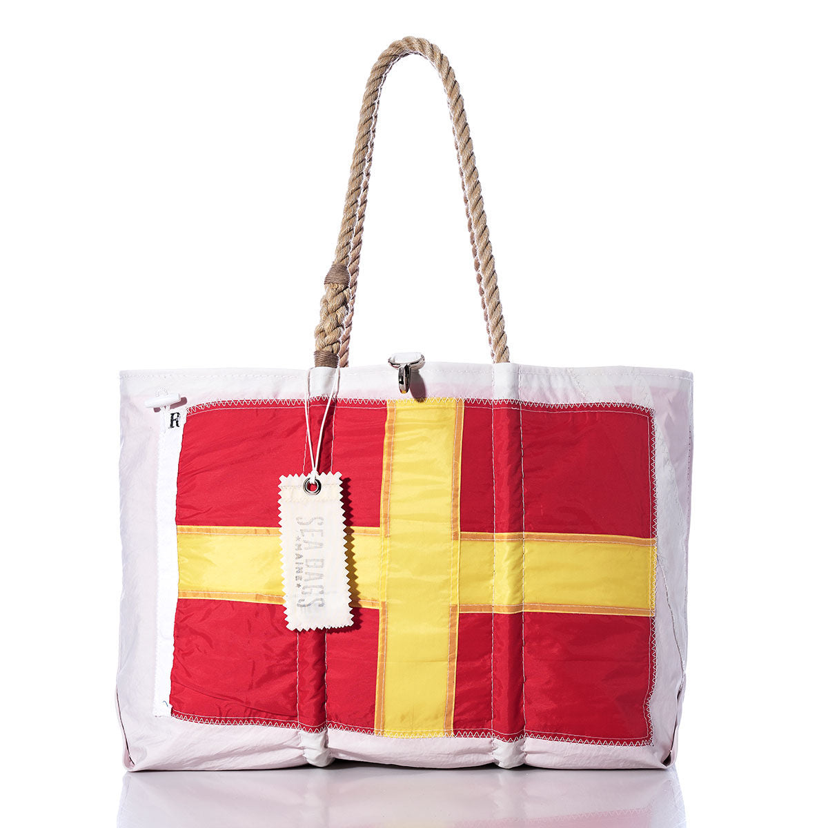 Sea Bags Romeo Signal Flag Large Tote—crafted from recycled sail cloth, this white tote features durable rope handles and is accented with a red and yellow cross on the front, inspired by vintage maritime signal flags. A white tag is attached to one of the handles. by Sea Bags