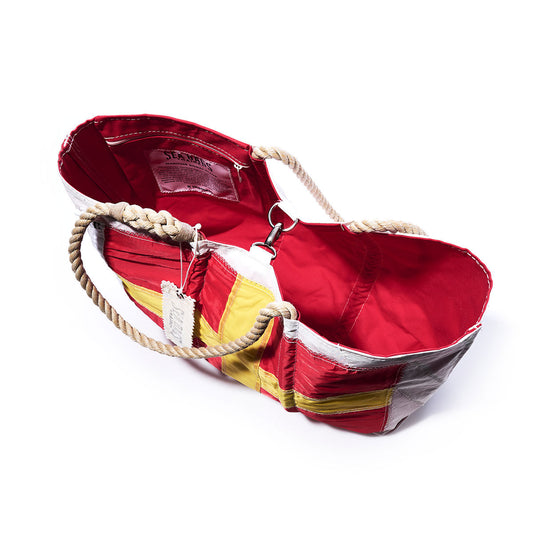 The Sea Bags Romeo Signal Flag Large Tote—crafted from recycled sail cloth in the style of maritime signal flags—features bold red, yellow, and white panels, sturdy rope handles, an interior label, and a metal hook inside. The tote is shown open against a white background. by Sea Bags