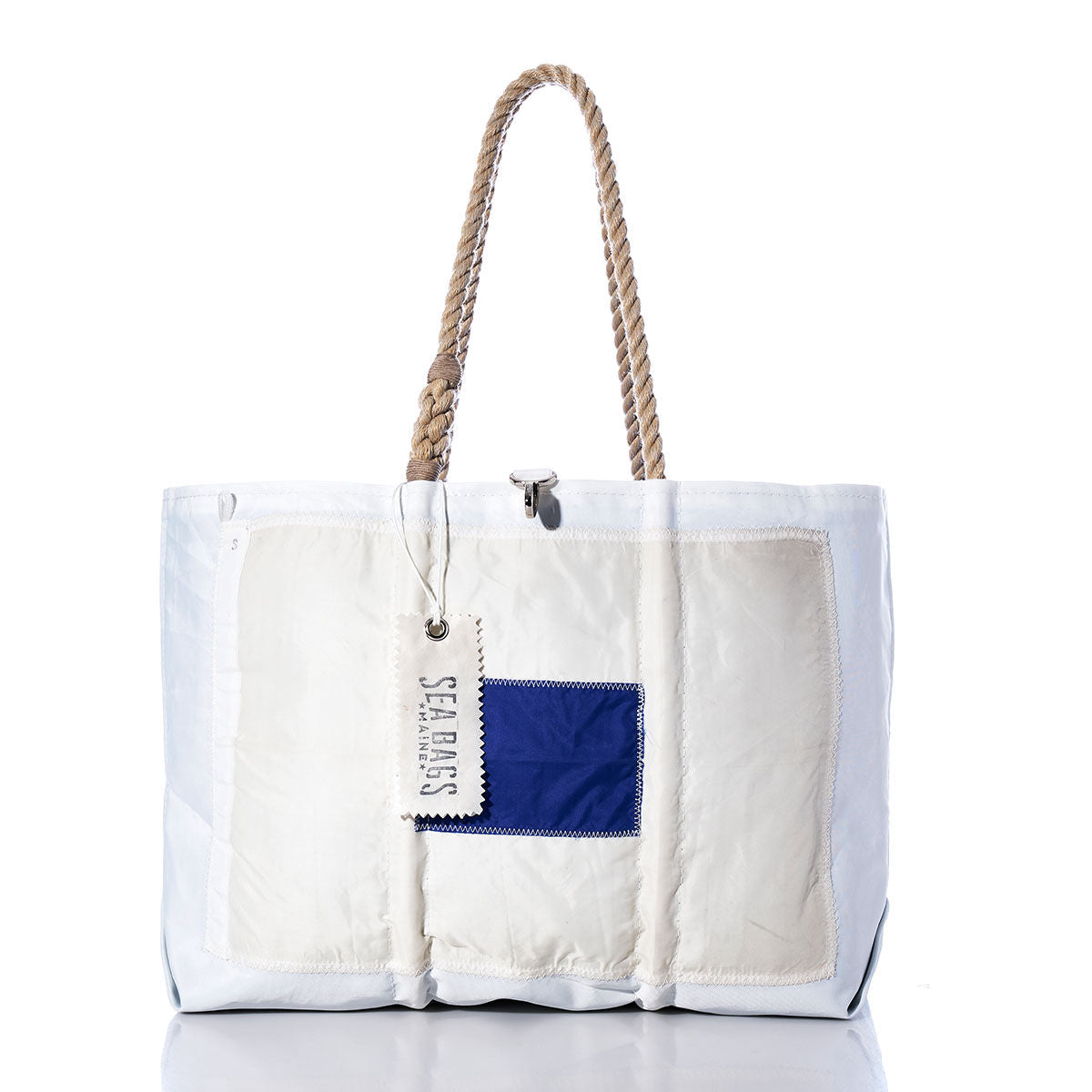 Sierra Signal Flag Large Tote by Sea Bags—a white tote bag with rope handles, made from recycled sail cloth, featuring a blue square patch on the front and a SEA BAGS tag attached to one handle, shown against a white background. by Sea Bags