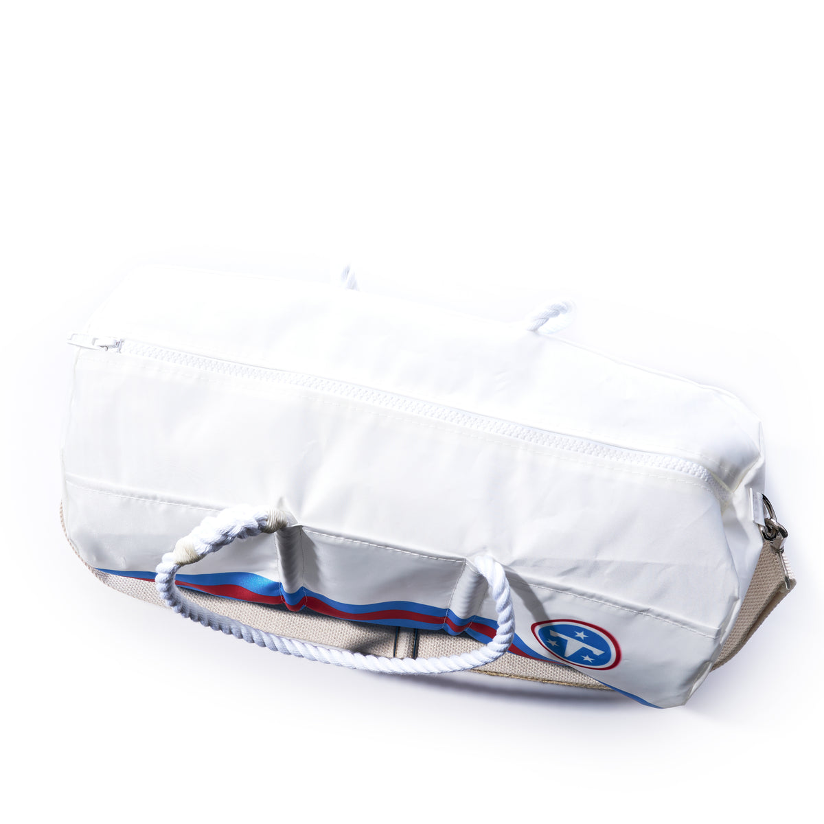 The Tennessee Titans Duffel by Sea Bags is a white duffel bag made from recycled sail cloth, featuring sturdy rope handles, a top zipper, and a small blue, red, and white patch near the bottom. Durable and stylish, this official NFL merchandise is perfect for Titans fans looking for something unique.