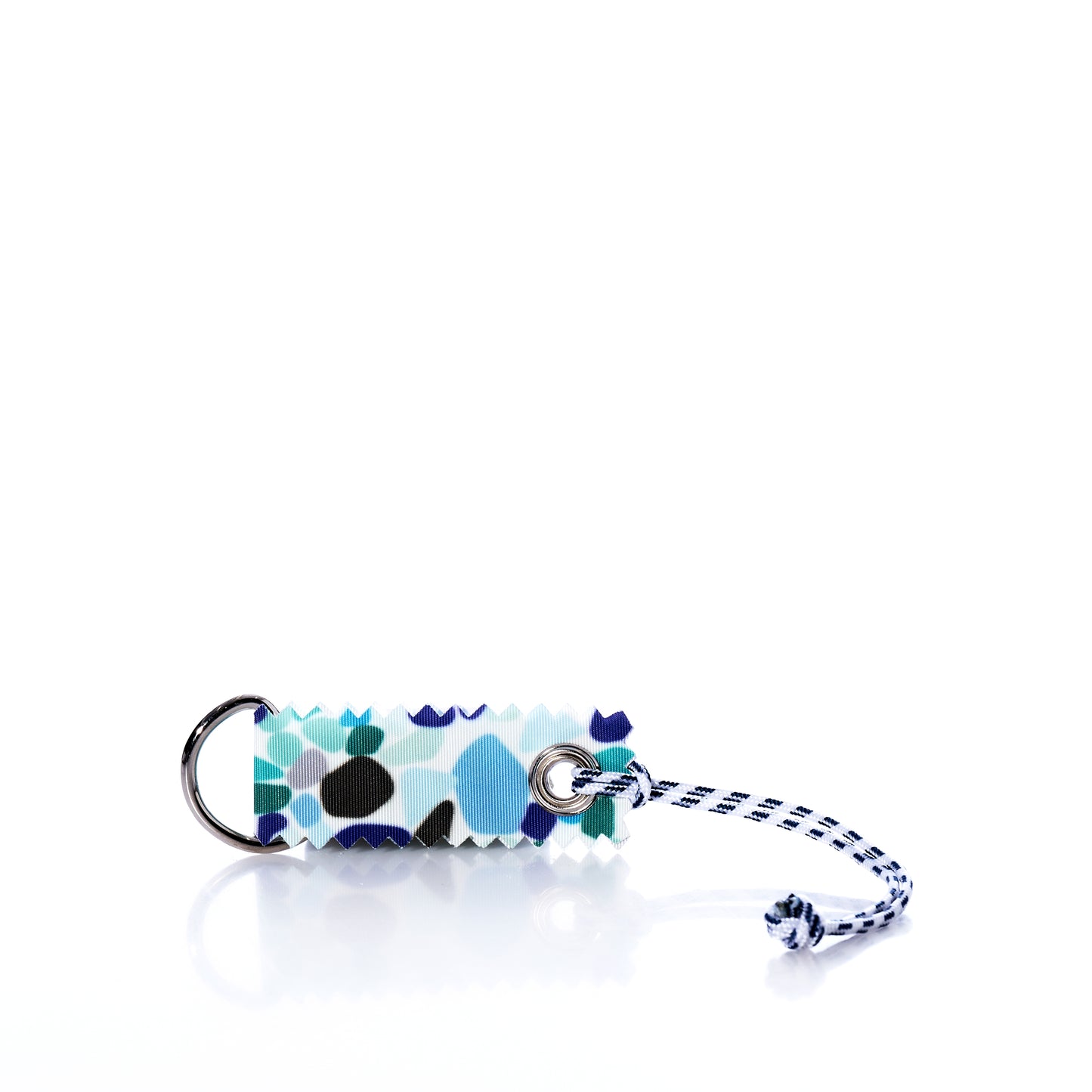 Sea Bags’ Sea Glass Print Sail Bag Charm features a rectangular design with a blue, black, and white abstract print, crafted from upcycled sail cloth for sustainable style. It is attached to a metal ring and finished with a blue-and-white cord, shown on a white background. by Sea Bags