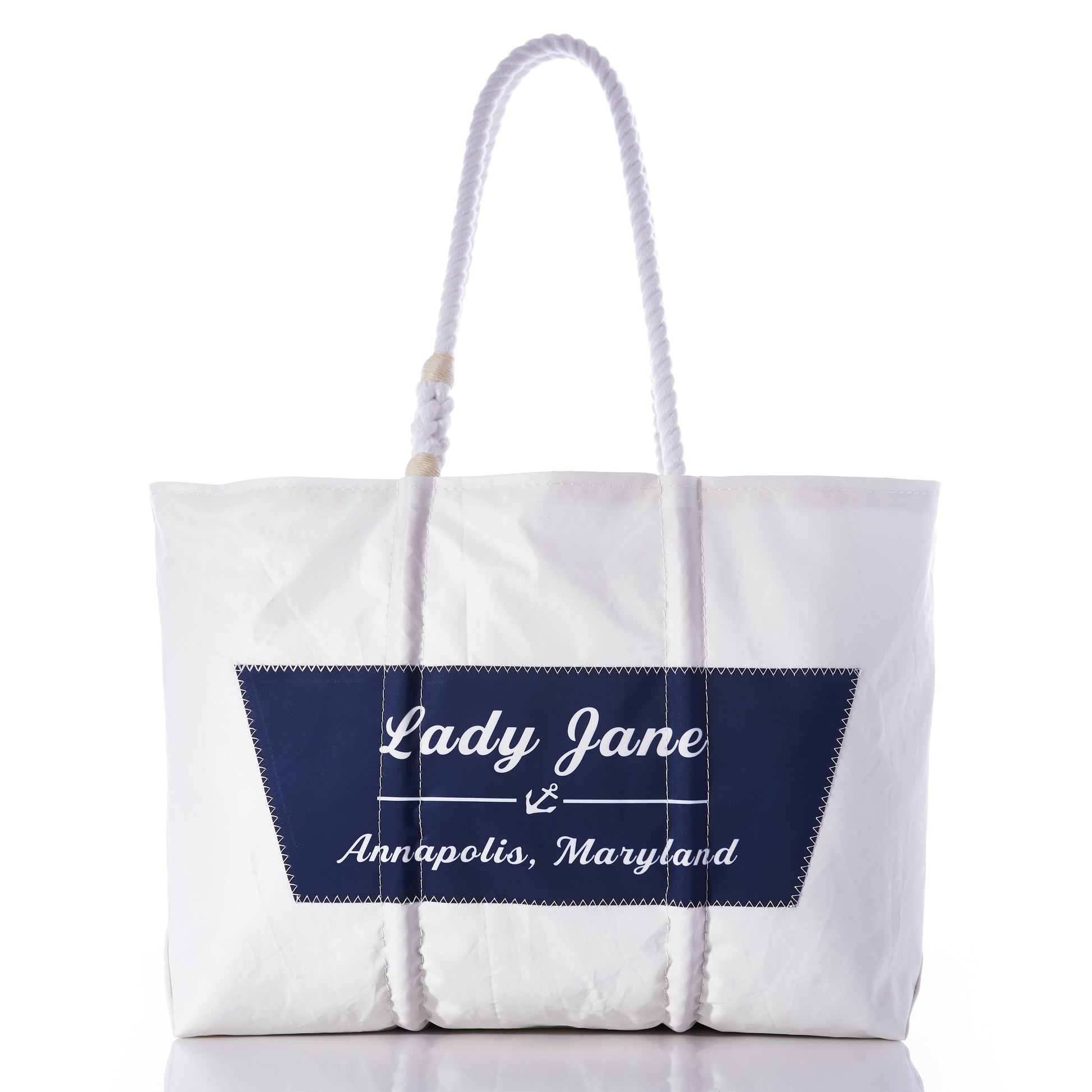 Sea Bags Custom Boat Name Tote in white, designed with rope handles and finished with a navy blue patch featuring an anchor and the text “Lady Jane Annapolis, Maryland” at the center. by Sea Bags