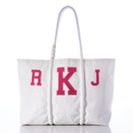 The Custom Monogram Tote by Sea Bags features white recycled sail cloth, rope handles, and pink monogram letters R K J on the front. Displayed against a white background, this personalized tote adds a thoughtful touch to any ensemble. by Sea Bags