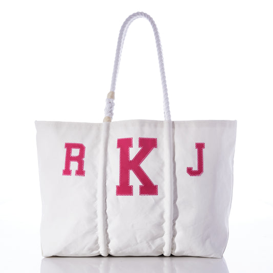 The Custom Monogram Tote by Sea Bags features white recycled sail cloth, rope handles, and pink monogram letters R K J on the front. Displayed against a white background, this personalized tote adds a thoughtful touch to any ensemble. by Sea Bags
