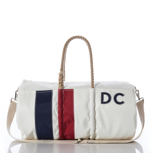 Sea Bags Custom Monogram Vertical Stripe Duffel, crafted from recycled sail cloth and photographed on a white background, features beige rope handles, a beige shoulder strap, a navy and red vertical stripe, and “DC” monogrammed on the front—a stylish and durable choice for any adventure. by Sea Bags