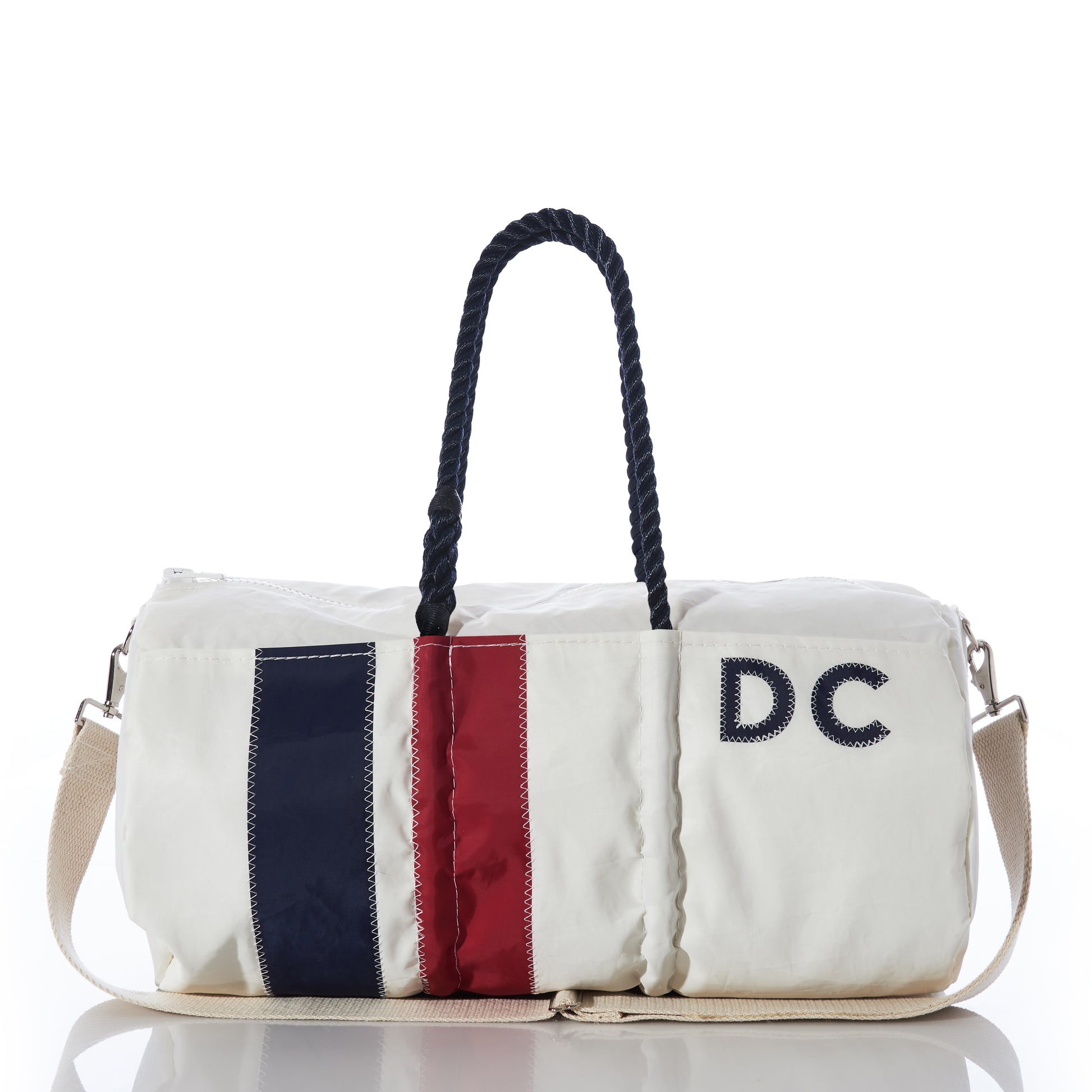 The Sea Bags Custom Monogram Vertical Stripe Duffel features navy and red vertical stripes on white recycled sail cloth, black rope handles, a beige shoulder strap, and DC embroidered on the side—offering a unique and eco-friendly bag with personalized style. by Sea Bags
