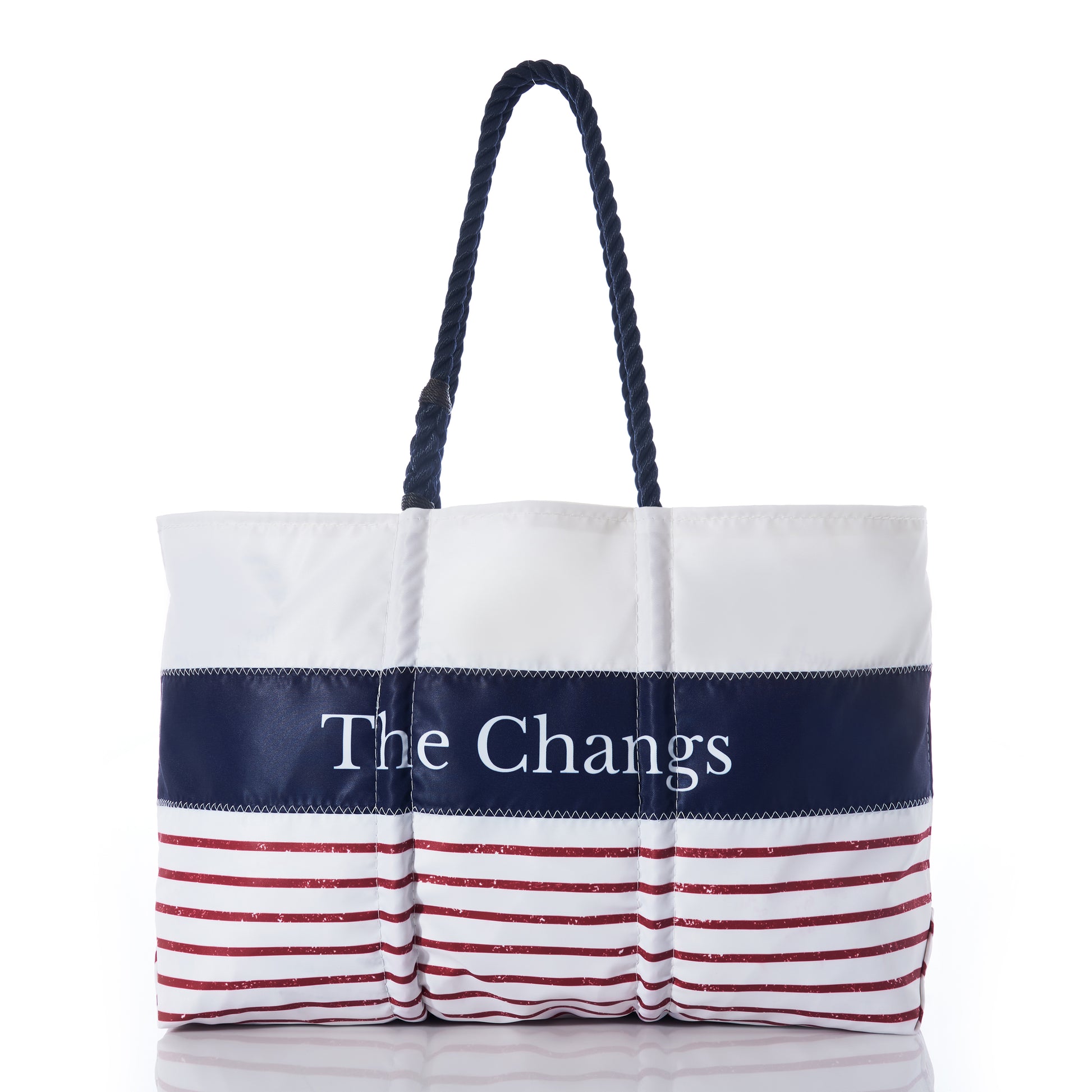 Introducing the Sea Bags Custom Mariner Stripe Tote—a white recycled sail cloth bag featuring a bold navy stripe personalized with The Changs, accented by striking red stripes along the bottom and finished with sturdy dark rope handles. This nautical-inspired tote combines eco-conscious craftsmanship with standout style. by Sea Bags