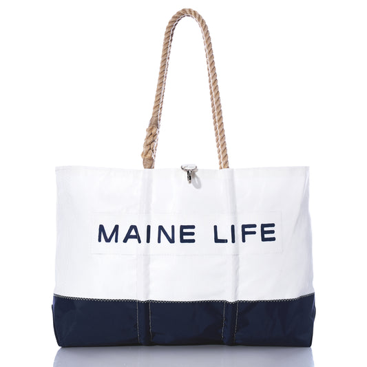 The Sea Bags Maine Life Large Tote is a spacious white and navy bag featuring sturdy rope handles and MAINE LIFE printed on the front, photographed against a white background. Inspired by Erin Ovalle’s signature Maine Life collection, this tote is perfect for everyday adventures. by Sea Bags