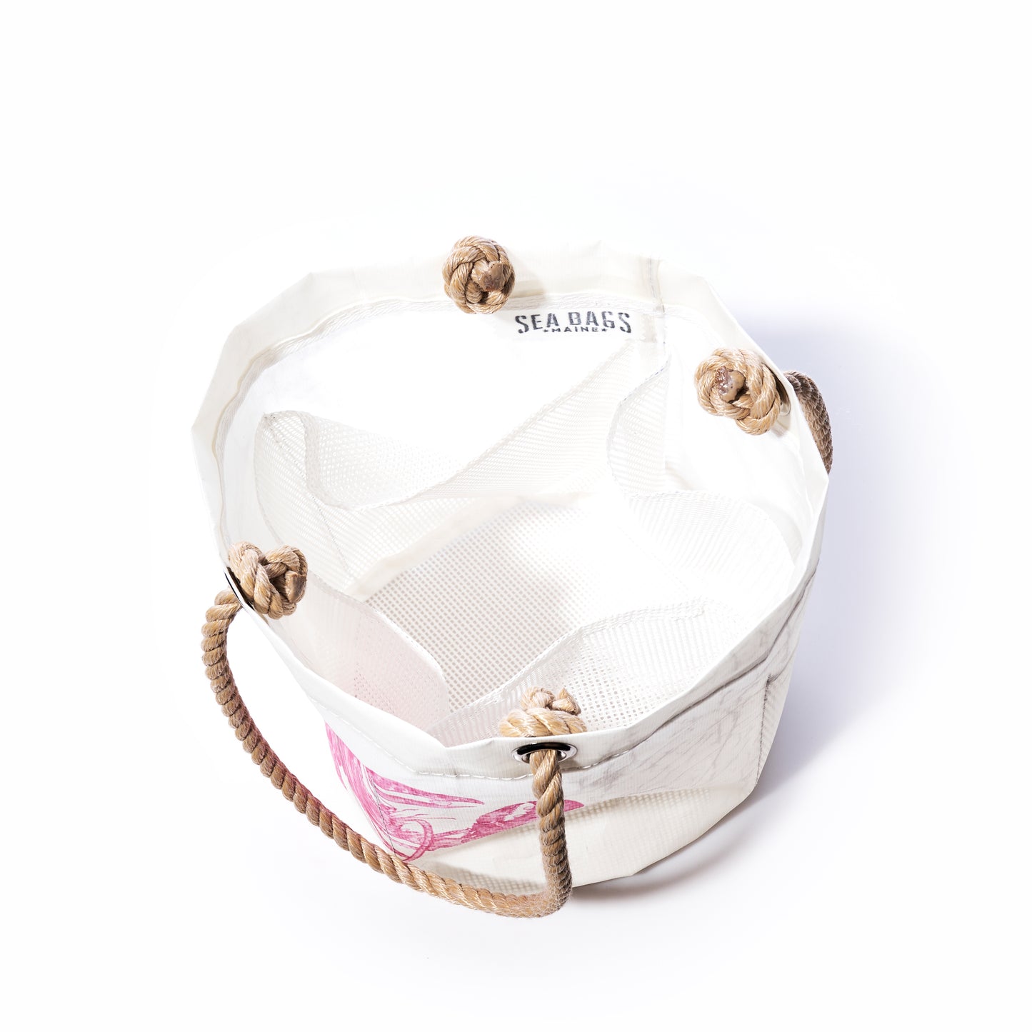 The Pink Lobster Beachcomber Bucket by Sea Bags is a white canvas beach bag crafted from recycled sail cloth, featuring sturdy rope handles with large knotted loops. The Sea Bags logo accents the inner rim, while a pink lobster design adds a distinctive touch to the exterior. This unique bucket bag blends style and sustainability—perfect for your seaside adventures. by Sea Bags