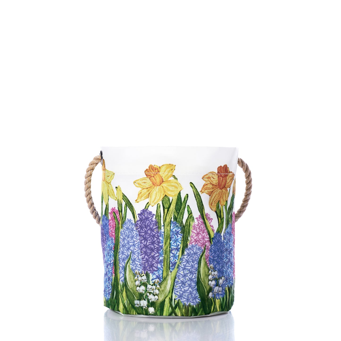 The Sea Bags Multi Floral Bucket Bag is a cylindrical white fabric storage basket with rope handles, made from recycled sail cloth and adorned with a vibrant print of daffodils, hyacinths, and lily of the valley—making it a sustainable Easter basket or a charming multi-floral bucket for your home. by Sea Bags