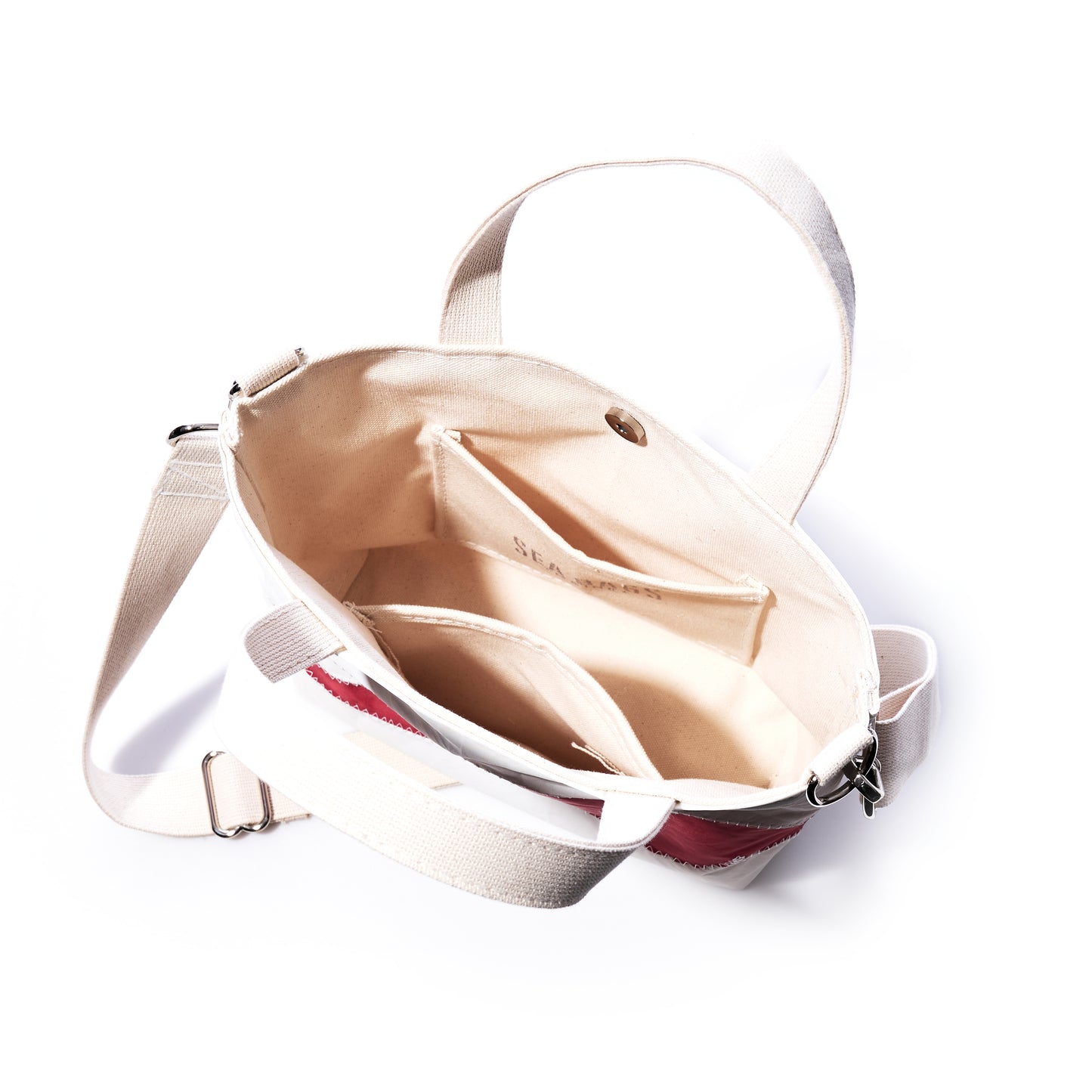 The Sea Bags Red Lobster Claw Crossbody Tote, crafted from recycled sailcloth with beige straps, is open to reveal a spacious interior with multiple pockets and a light-colored lining—an eco-friendly everyday bag designed for organization. by Sea Bags