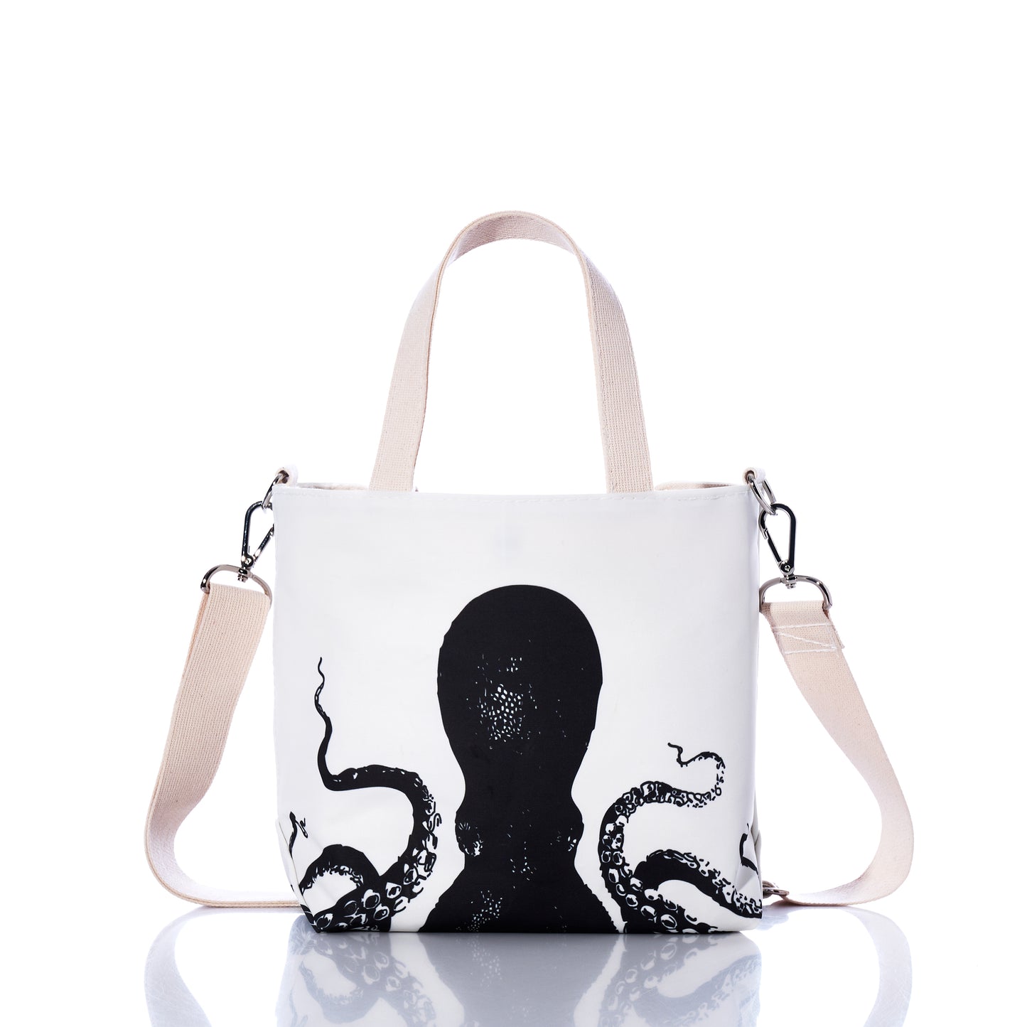 The Sea Bags Octopus Crossbody Tote, crafted from recycled sailcloth, features a black octopus illustration, beige handles, and an adjustable beige shoulder strap, and is displayed on a reflective surface. by Sea Bags