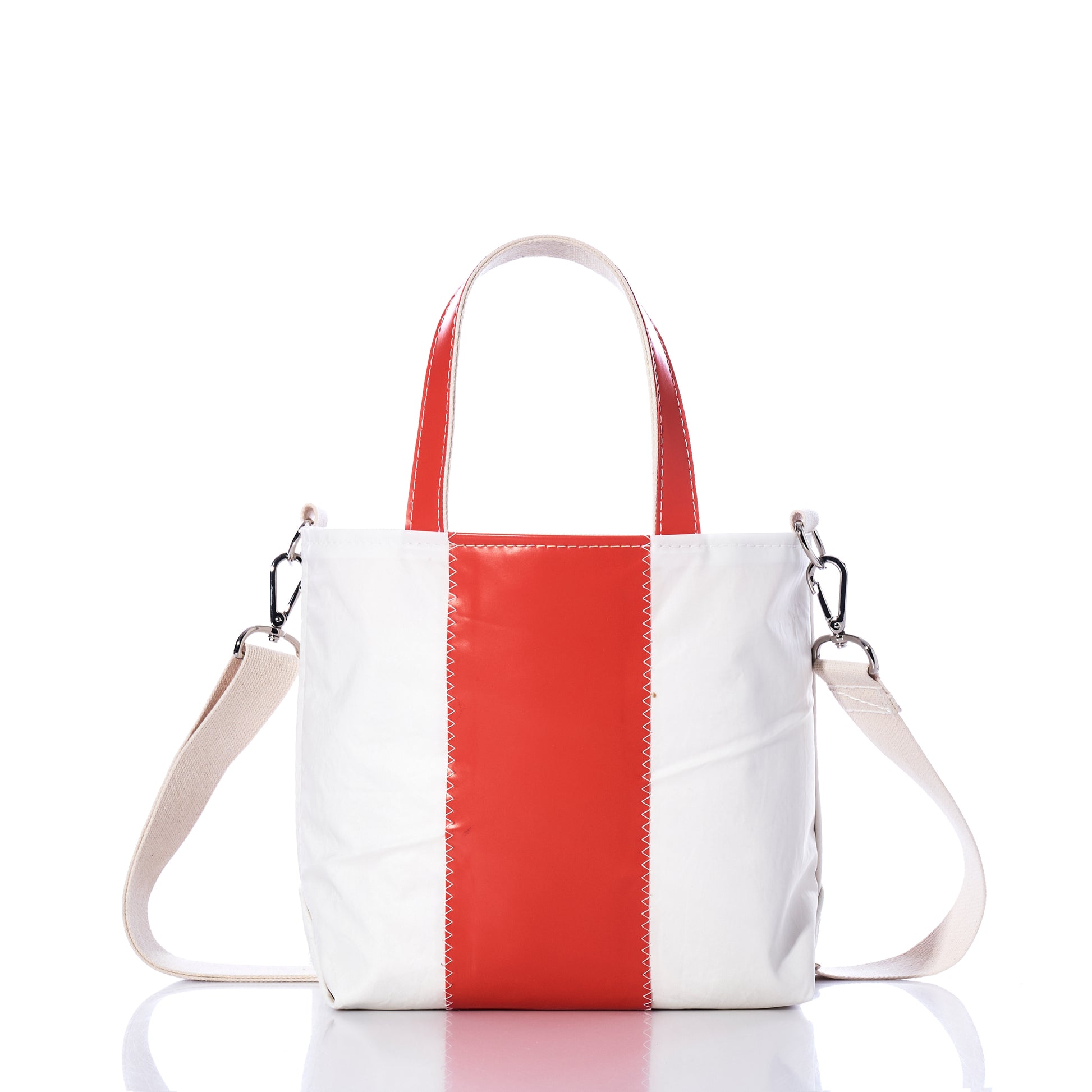 The Trapline Crossbody Tote by Sea Bags is a white recycled sail tote featuring a vertical red stripe, red handles, and a detachable beige shoulder strap—offering a stylish and sustainable bag option, as shown on a white background. by Sea Bags