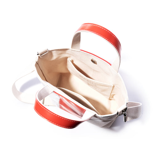 Trapline Crossbody Tote by Sea Bags features an open canvas design with red handles, a beige interior, zip closure, and multiple compartments including a small inside pocket—crafted sustainably for versatile daily use. by Sea Bags