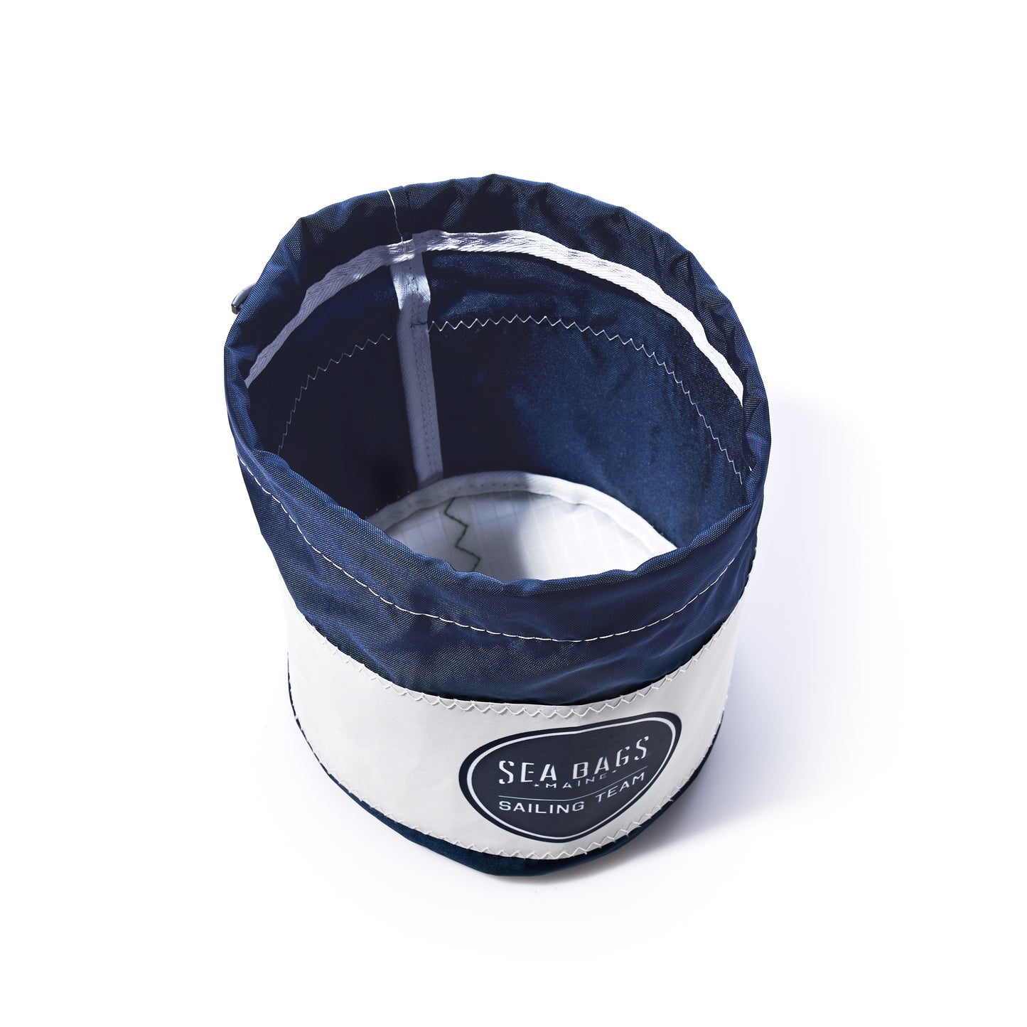 The Race Day Ditty Bag by Sea Bags is a navy blue and white fabric bucket sailing bag, featuring a Sailing Team patch on the front. Crafted from recycled sail bags, it is photographed against a white background. by Sea Bags