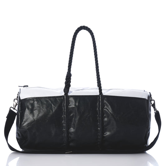 Introducing the Black Dragon Duffel by Sea Bags—a black and white travel duffel bag made from recycled sail cloth, designed with rope handles and a detachable shoulder strap. Shown on a reflective surface against a white background, this water-resistant bag combines style and durability, making it the perfect companion for your next adventure. by Sea Bags