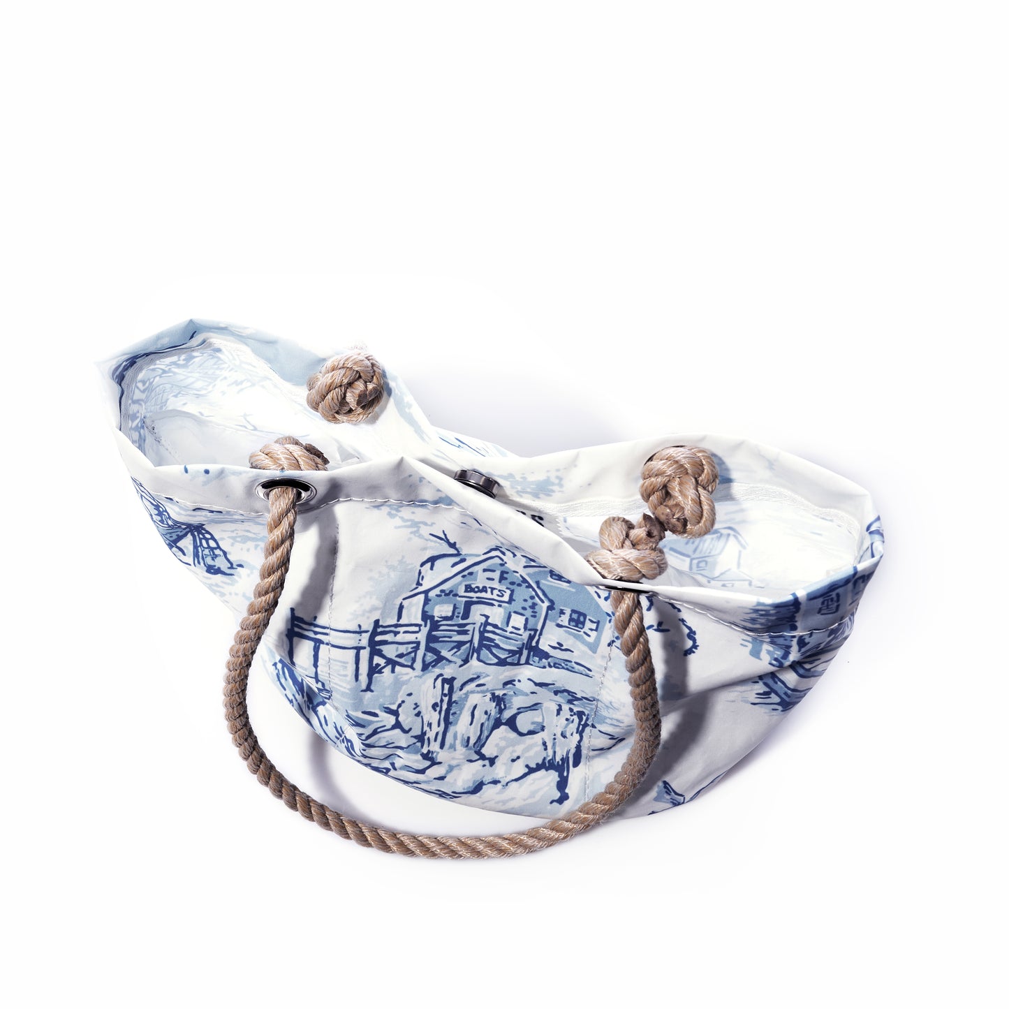 The Sea Bags Maine Fishing Village Essential Handbag, featuring a spacious design with blue and white nautical patterns, is crafted from recycled sail cloth and finished with sturdy rope handles and classic nautical knots—capturing the enduring allure of the Maine coast—all showcased against a crisp white background. by Sea Bags