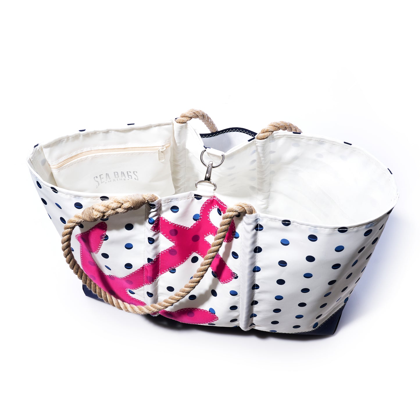 The Fuchsia Anchor  Summer Dots Ogunquit Beach Tote by Sea Bags is a white beach bag adorned with vibrant pink dots and a bold fuchsia anchor, featuring sturdy rope handles and an interior zip pocket. Expertly crafted from recycled sail cloth, it is shown photographed on a white background. by Sea Bags