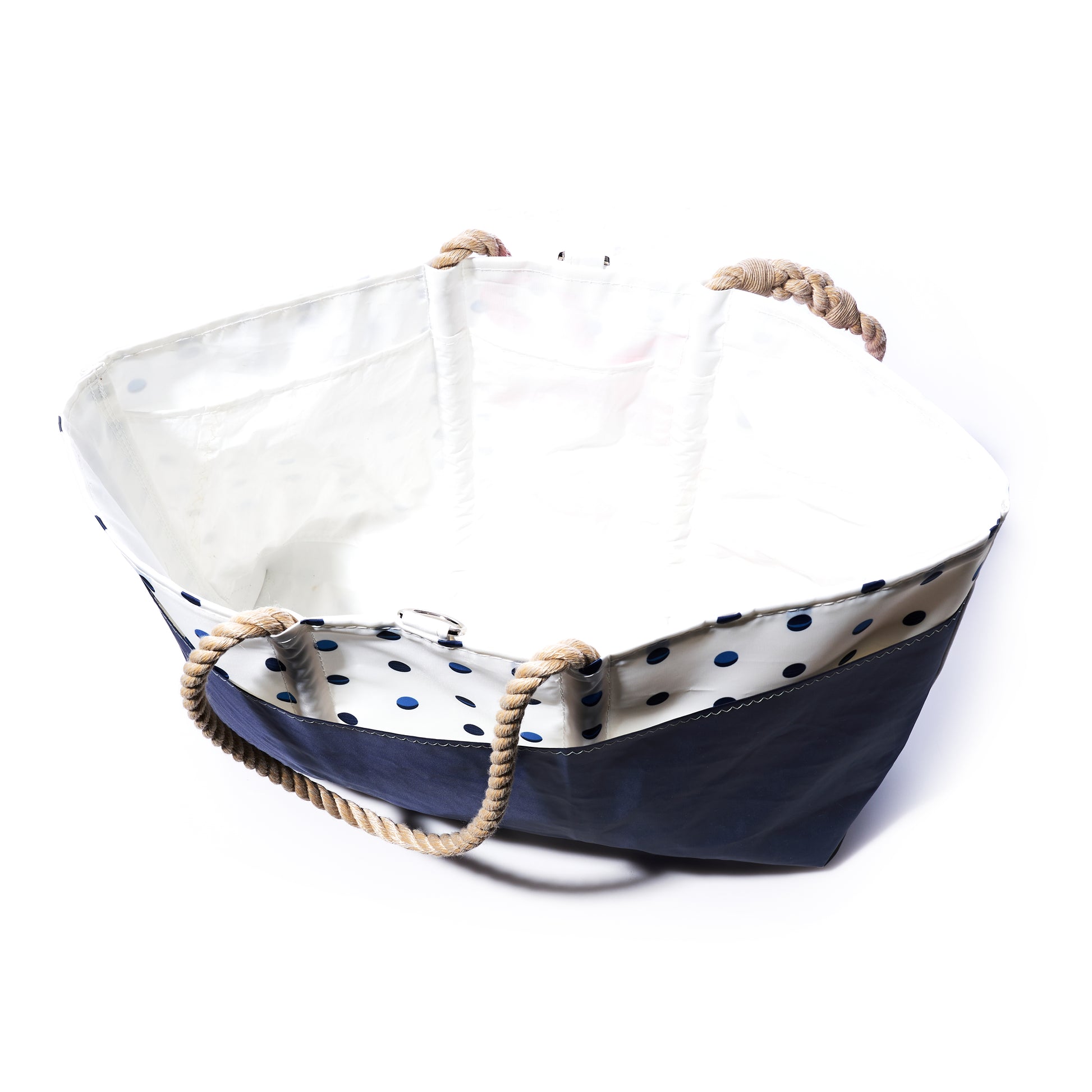 The Fuchsia Anchor  Summer Dots Ogunquit Beach Tote by Sea Bags is a spacious, open beach bag made from recycled sail cloth, featuring a vibrant navy blue bottom, a white upper section decorated with fuchsia and blue polka dots, sturdy rope handles, and photographed on a white background. by Sea Bags