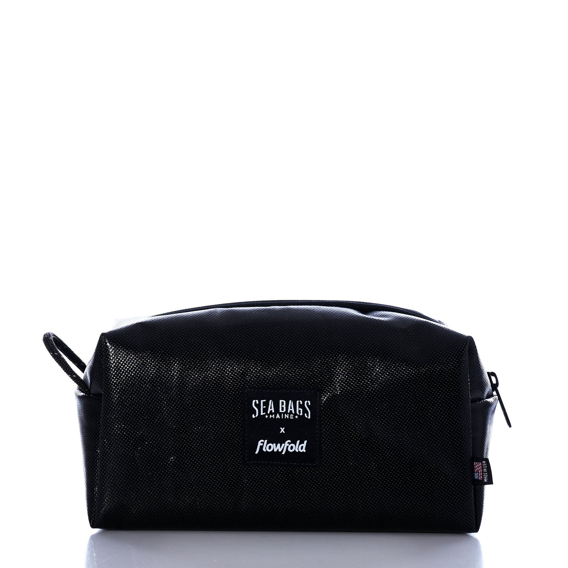 A Black Dragon Toiletry Bag by Sea Bags, featuring a water-resistant zippered design and branded label on the front, photographed against a white background. by Sea Bags