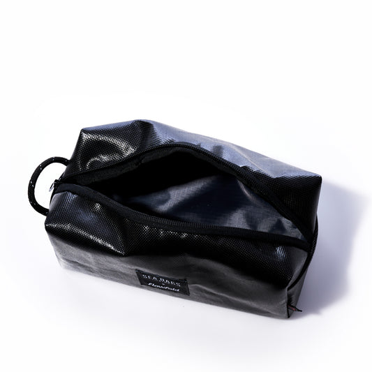 A Black Dragon Toiletry Bag by Sea Bags, featuring a black, water-resistant textured surface, sits open on a white background and displays its empty interior along with a side loop handle. by Sea Bags