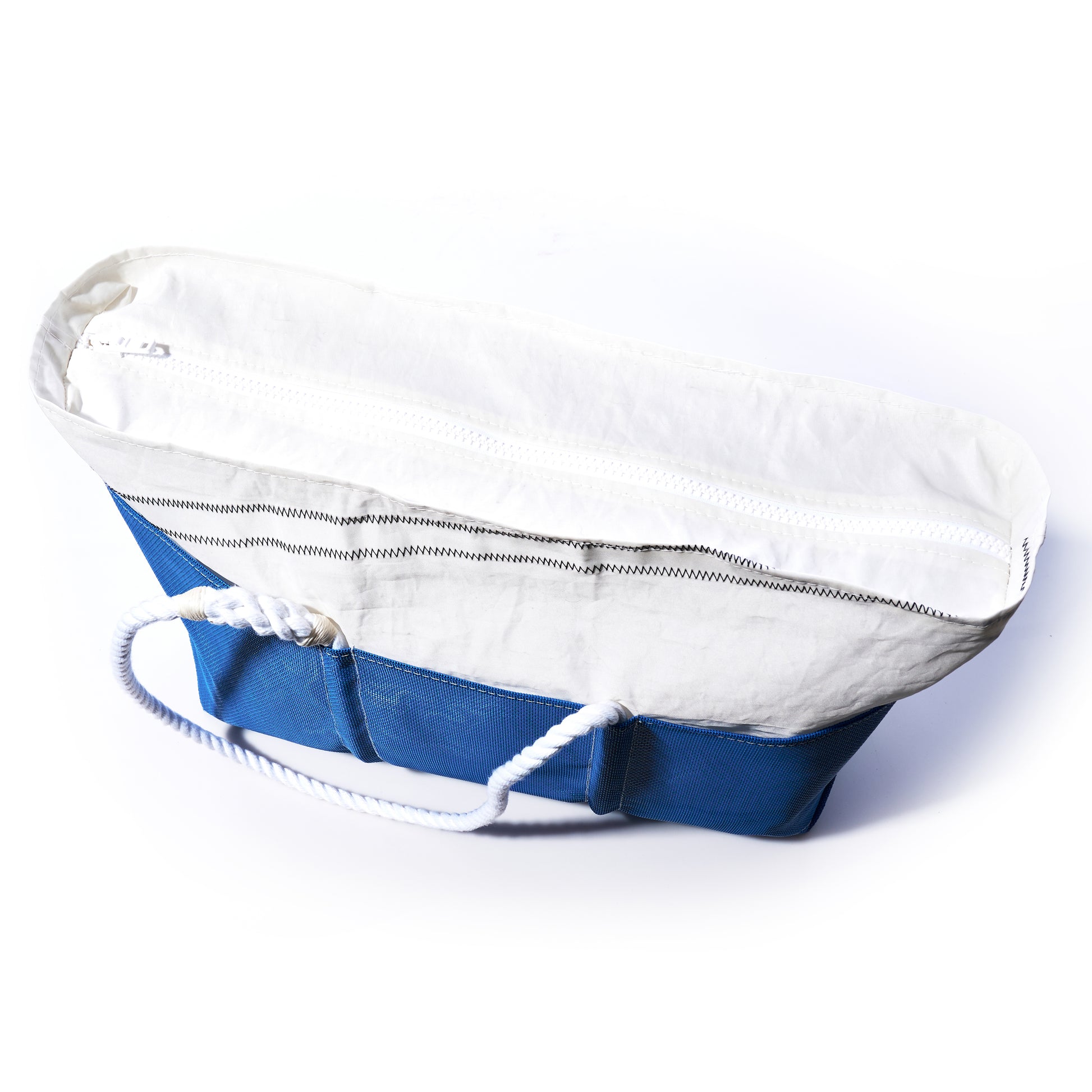 The Harbor Blue Beachcomber Tote by Sea Bags, featuring a blue and white design crafted from recycled sailcloth, a zipper closure, and sturdy white rope handles, is shown from above on a white background. by Sea Bags