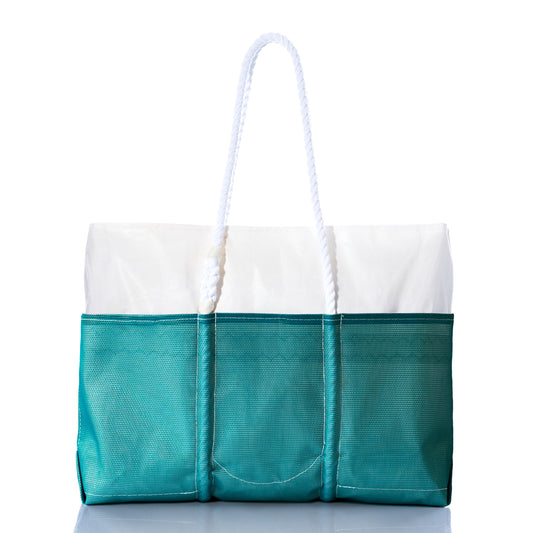 The Sea Bags Ocean Teal Beachcomber Tote is a teal and white sand-proof beach bag featuring three exterior pockets and two white rope handles, shown against a white background. by Sea Bags