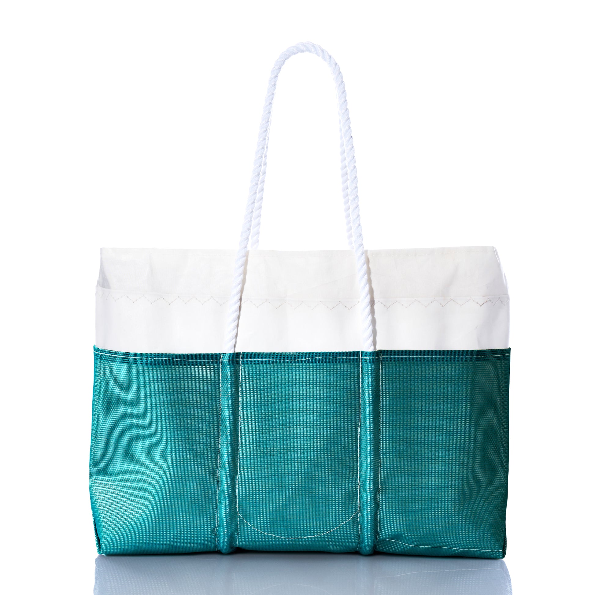 The Ocean Teal Beachcomber Tote by Sea Bags is displayed against a white background, featuring recycled sail material in teal and white, rope handles, three exterior pockets, and a reflective underside. This sand-proof beach bag seamlessly blends style with functionality, making it the ideal companion for your seaside adventures. by Sea Bags