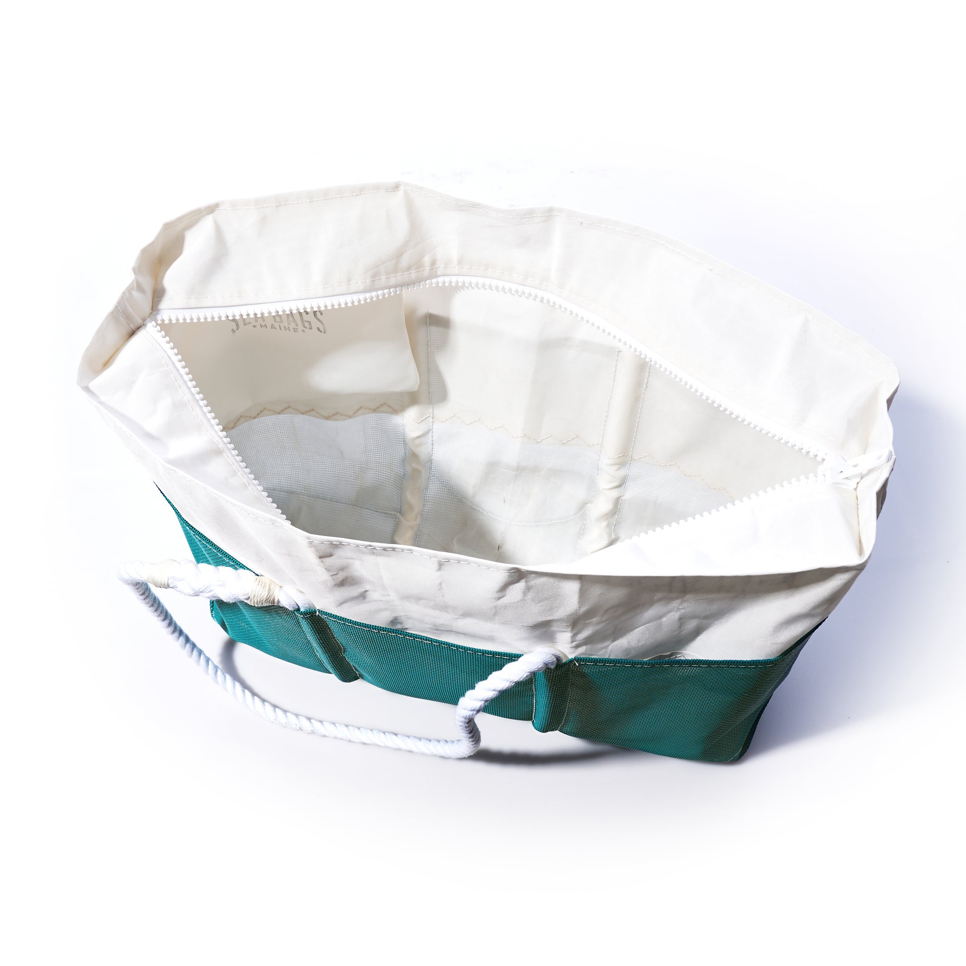 The Ocean Teal Beachcomber Tote by Sea Bags is shown open from above on a white background, featuring green and white canvas with sturdy white rope handles and a spacious, empty interior—a perfect sand-proof beach bag for your summer adventures. by Sea Bags