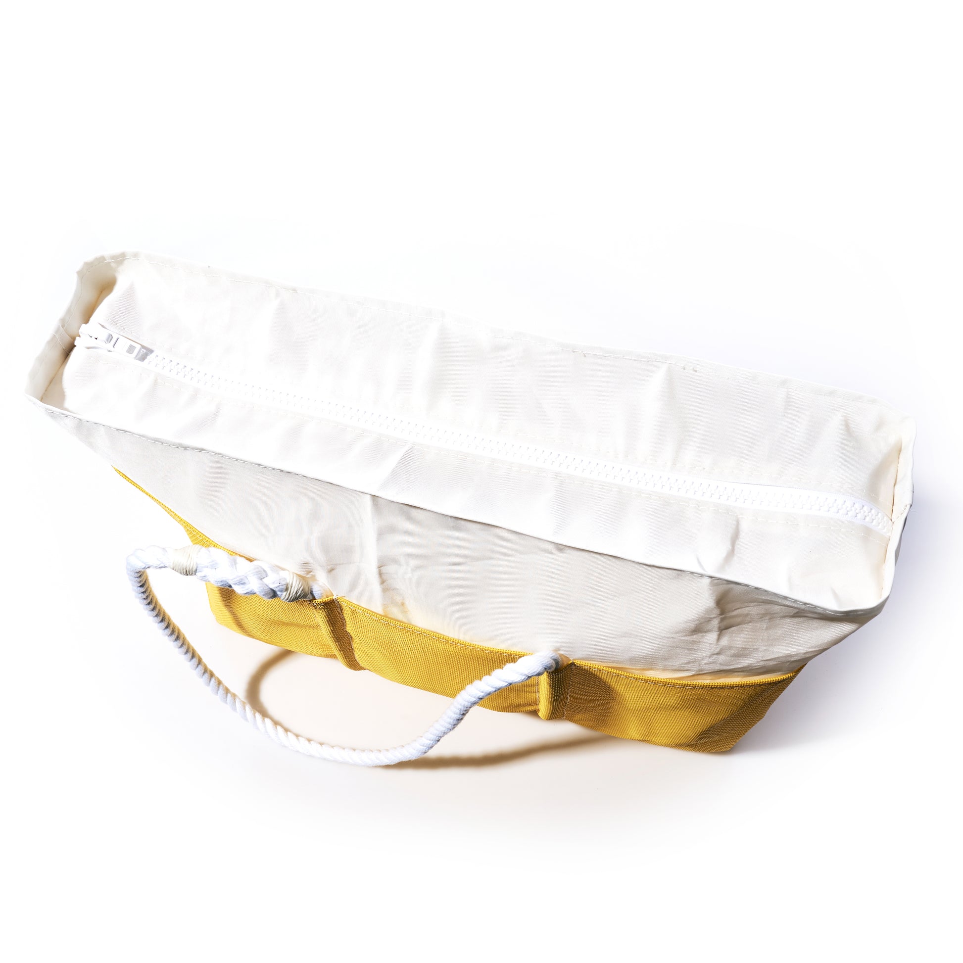 The Goldenrod Beachcomber Tote by Sea Bags is a yellow and white canvas beach bag featuring sturdy rope handles and a white zipper, photographed on a white background. by Sea Bags
