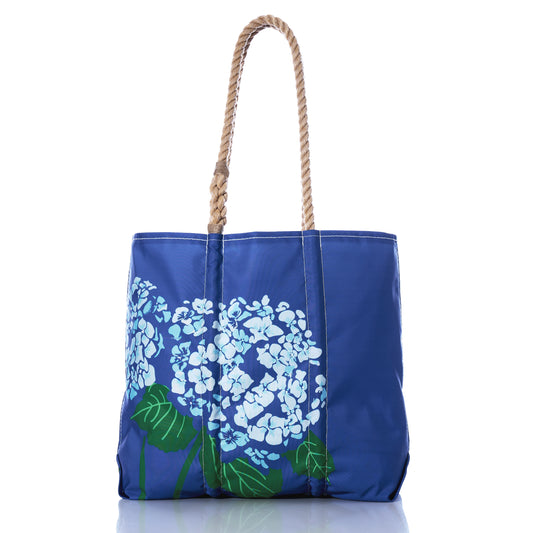 Introducing the Harbor Blue Hydrangea Medium Tote by Sea Bags—a stylish coastal accessory featuring a rope handle and a hydrangea flower design, expertly crafted from recycled sailcloth. Photographed on a white background, this tote seamlessly blends sustainability and style for your everyday adventures. by Sea Bags