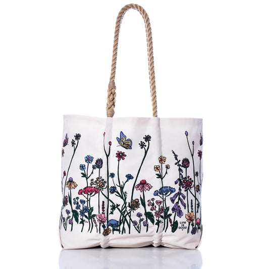 Sea Bags Life is Good Wildflowers Medium Tote, handcrafted in Maine from recycled sail bag materials, features rope handles and a vibrant wildflower and butterfly print along the bottom half, shown on a white background. by Sea Bags