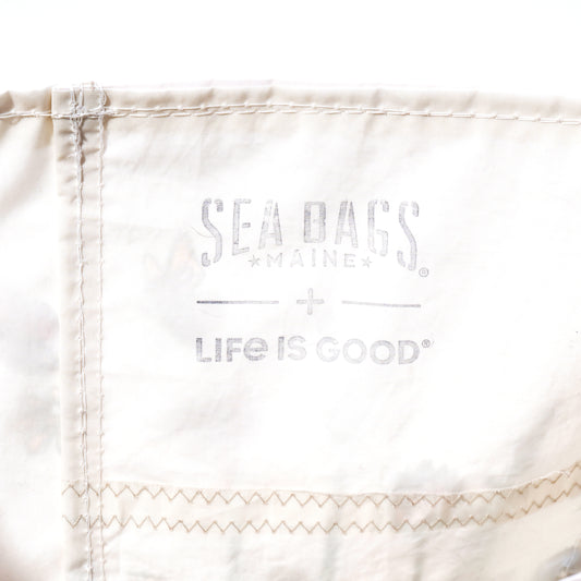 Handcrafted in Maine from recycled sail bag materials, the Life is Good Wildflowers Medium Tote by Sea Bags features white fabric with visible stitching and is printed with faded gray SEA BAGS MAINE and LIFE IS GOOD logos. by Sea Bags