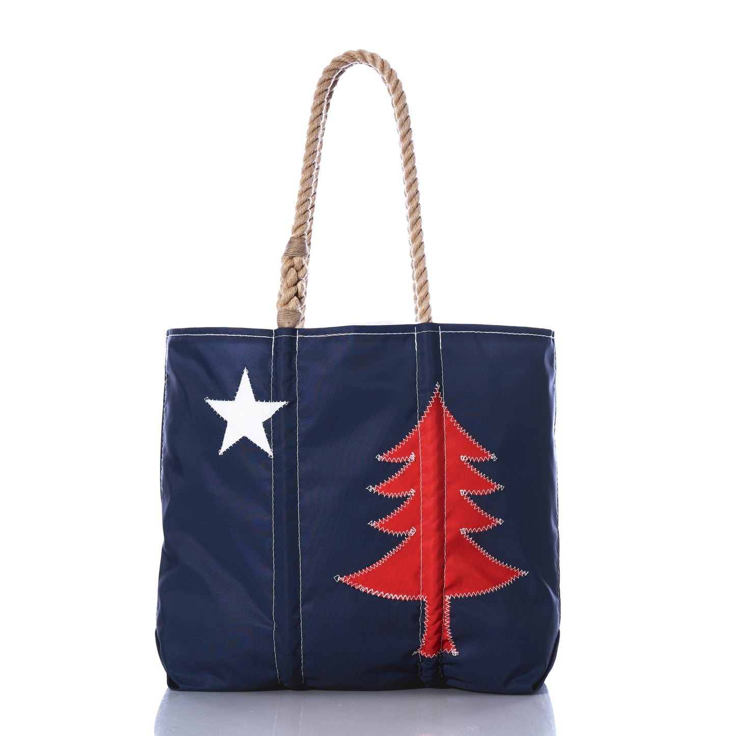 Introducing the Sea Bags 250th Patriotic Pine Medium Tote: crafted from recycled sailcloth in classic Maine style, this navy blue tote bag features sturdy rope handles, a white star on the left, and a red pine tree on the right for a striking patriotic look. by Sea Bags