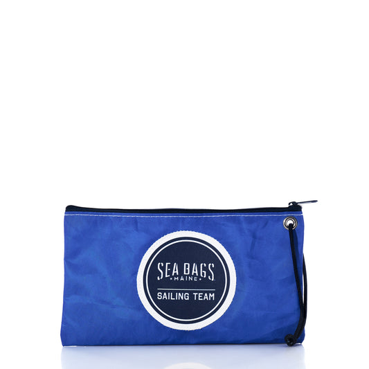 The Sea Bags Race Day Large Wristlet is a blue zippered pouch with a black strap and showcases a circular Sea Bags Sailing Team logo on the front. Crafted from recycled sail bags, this nautical wristlet combines eco-friendly materials with distinctive maritime style. by Sea Bags