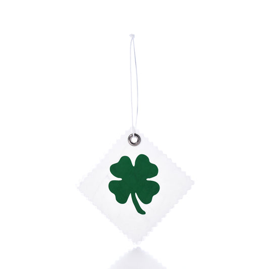 The Four Leaf Clover Sail Cloth Gift Tag by Sea Bags features a white square design crafted from sail cloth, adorned with a green four-leaf clover motif and suspended by a string against a white background—making it an eco-friendly and charming gift accessory or distinctive clover bag charm. by Sea Bags