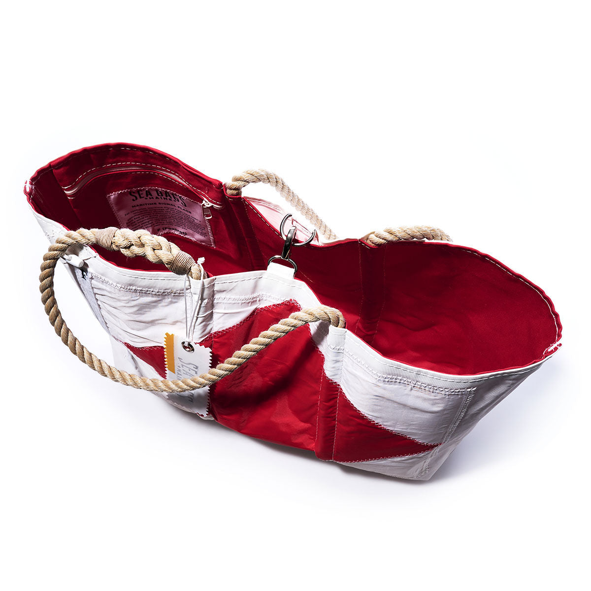 The Foxtrot Signal Flag Large Tote by Sea Bags features bold red and white panels with rope handles and a visible tag, crafted from recycled sail cloth. Shot on a white background, the bag’s striking red interior is inspired by the vibrant hues of maritime signal flags. by Sea Bags