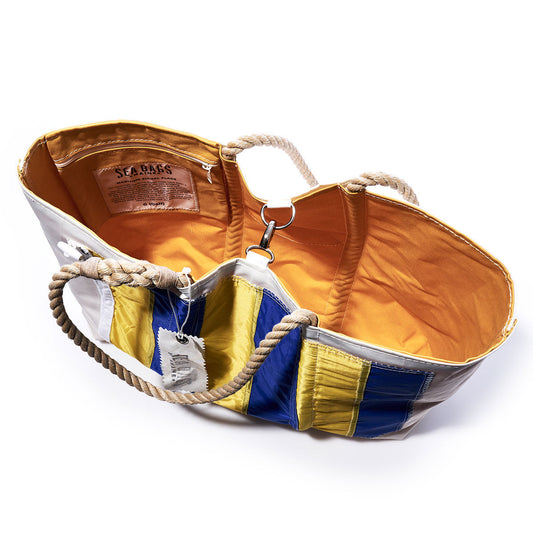 Introducing the Sea Bags Golf Signal Flag Large Tote: crafted from recycled sail cloth, this spacious tote features sturdy rope handles, a cheerful yellow interior, and striking blue, yellow, and white exterior panels inspired by vibrant maritime signal flags. Inside, you’ll find the signature Sea Bags label—a perfect blend of nautical spirit and sustainable style. by Sea Bags
