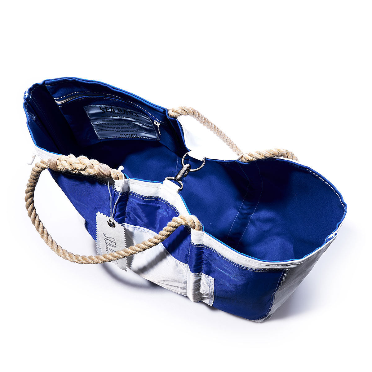 The Sea Bags Papa Signal Flag Large Tote features a blue and white design with rope handles, an open top revealing its spacious interior and a convenient small pocket. Handcrafted from recycled sail cloth, this tote draws inspiration from maritime signal flags, capturing classic nautical charm. by Sea Bags