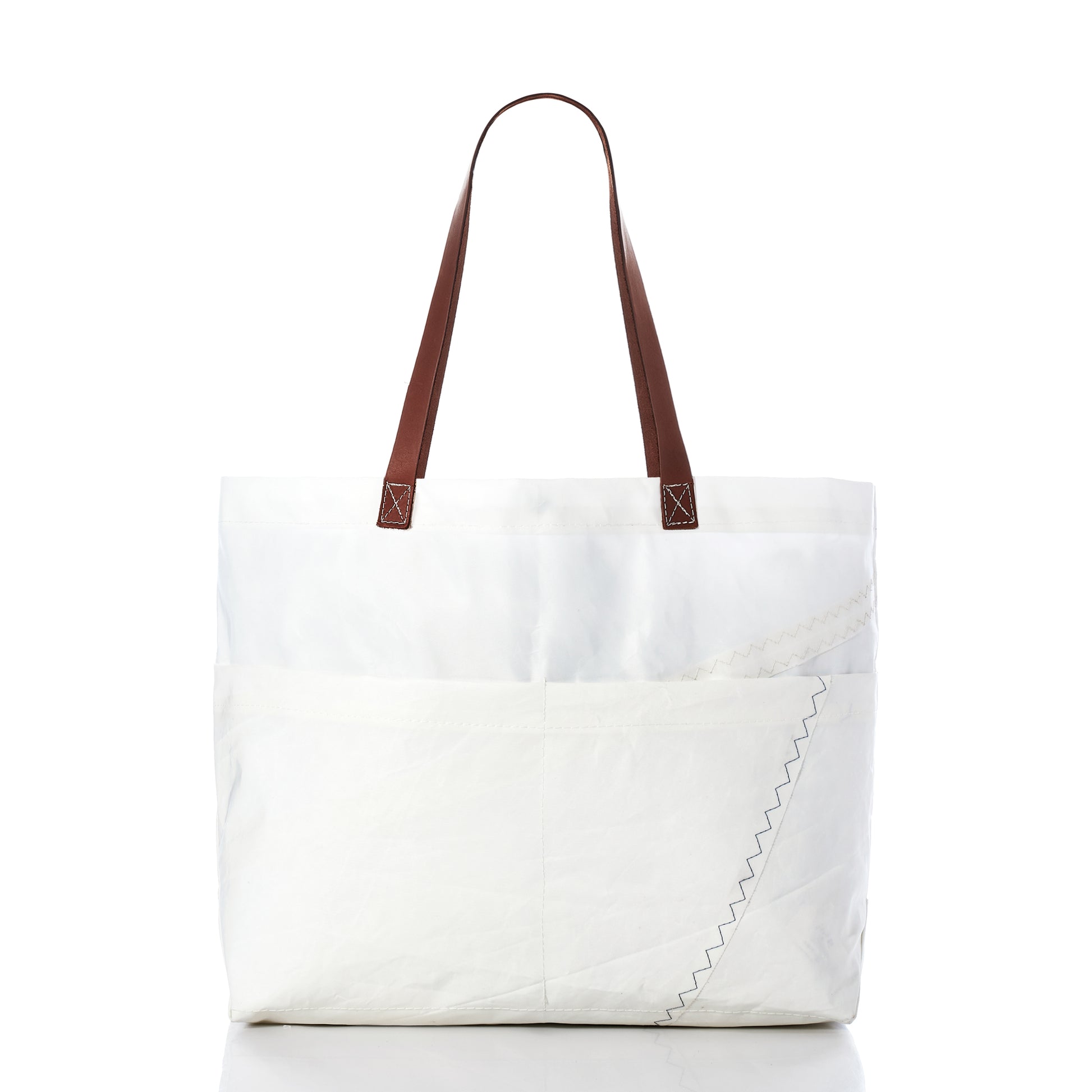 Sea Bags’ Large Market Tote, crafted from white recycled sail with brown leather handles, features an exterior pocket and visible zigzag stitching detail, shown against a plain white background. by Sea Bags