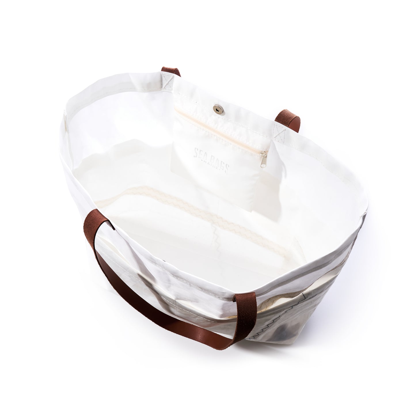 The Sea Bags Large Market Tote features a white exterior, brown leather handles, an interior pocket with a button closure, and visible side stitching. Made from recycled sail cloth, this spacious tote is open and empty. by Sea Bags