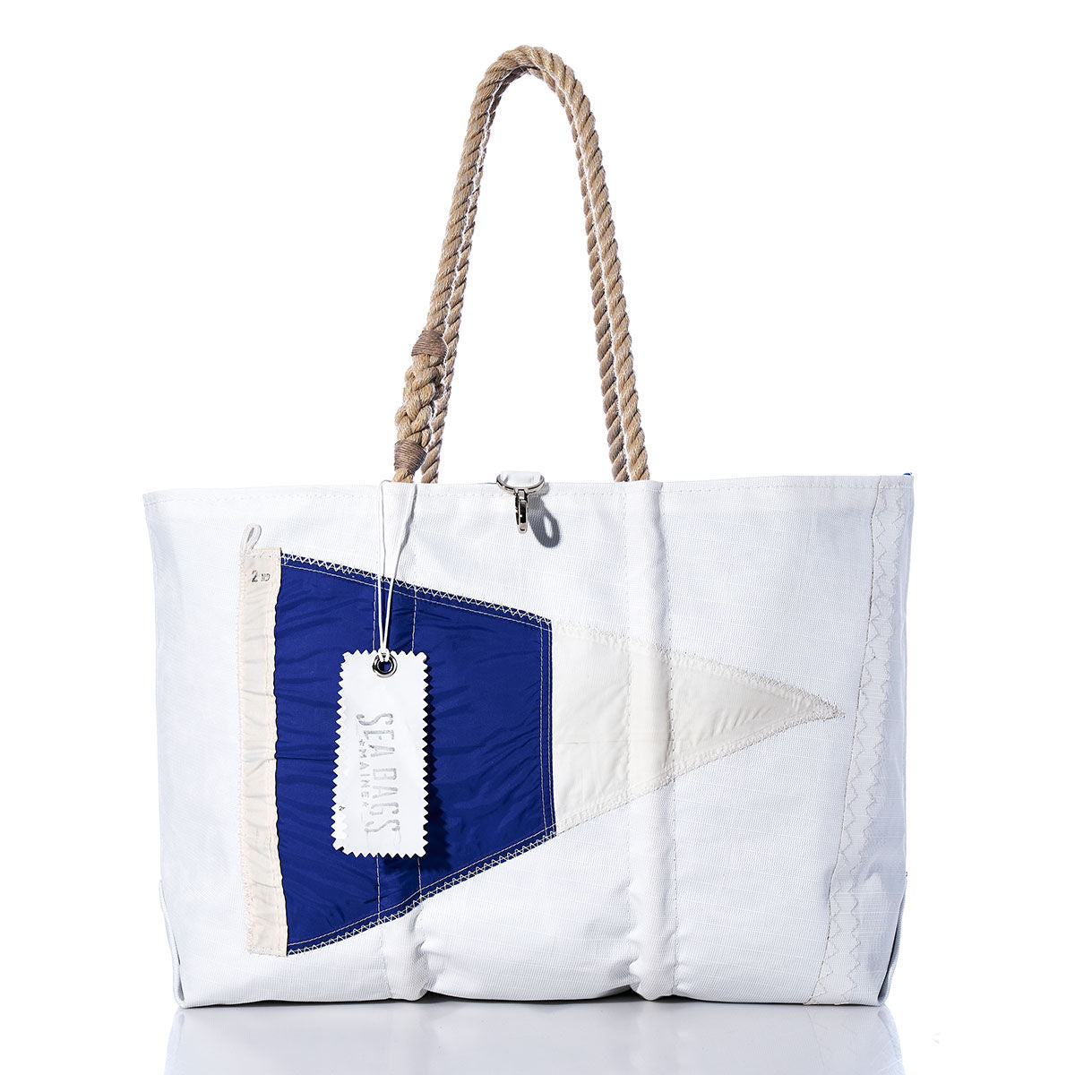 Introducing the 2nd Repeat Signal Flag Large Tote by Sea Bags—a handcrafted white canvas tote bag featuring sturdy rope handles, a striking blue and white signal flag design inspired by maritime pennants on the front, and a SAILORS tag attached to the handle. Crafted from vintage sail cloth, this classic tote blends nautical heritage with timeless seafaring style. by Sea Bags